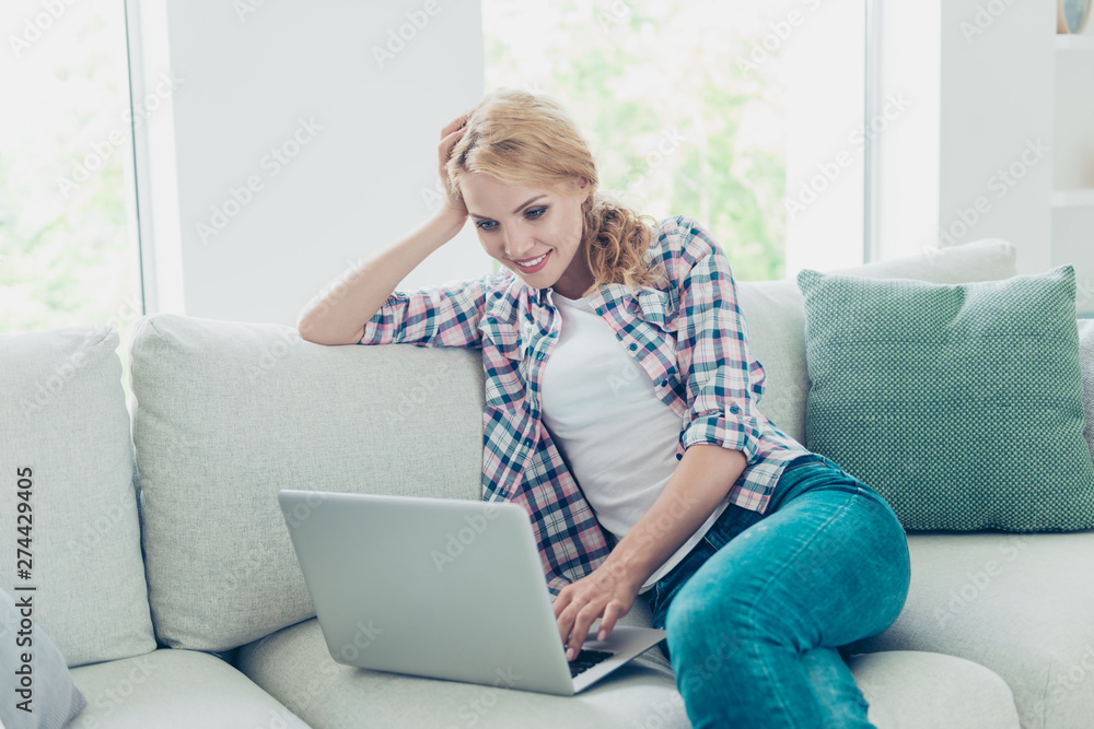 Portrait of her she nice-looking attractive lovely charming cute cheerful wavy-haired girl wearing checked shirt sitting on divan making video call at white light style interior living-room hotel Portrait of her she nice-looking attractive lovely charming cute cheerful wavy-haired girl wearing checked shirt sitting on divan making video call at white light style interior living-room hotel