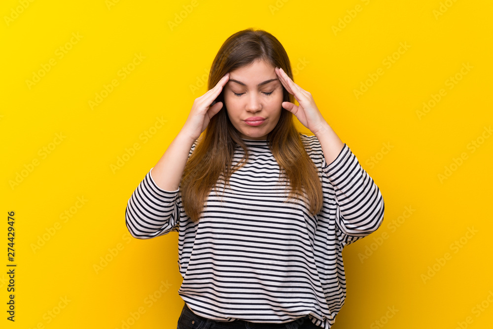 Young girl over yellow wall with headache Young girl over yellow wall with headache
