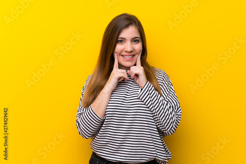 Young girl over yellow wall smiling with a happy and pleasant expression
