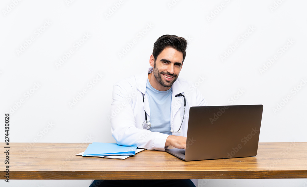 Young doctor man with his laptop over isolated wall Young doctor man with his laptop over isolated wall