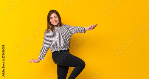 Young girl  jumping over isolated yellow background © luismolinero
