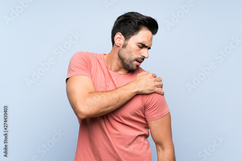 Canvas Print Handsome young man in pink shirt over isolated blue background suffering from pa
