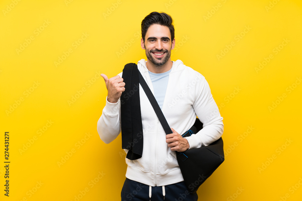 Young sport man over isolated yellow wall pointing to the side to present a product Young sport man over isolated yellow wall pointing to the side to present a product