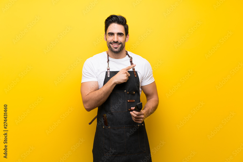 Young hairdresser man over isolated yellow background pointing to the side to present a product Young hairdresser man over isolated yellow background pointing to the side to present a product