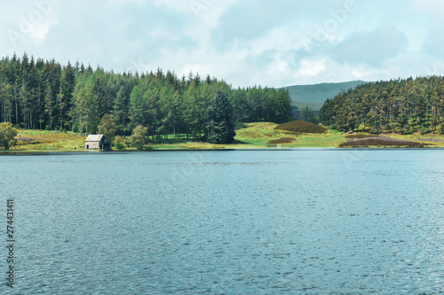 lake in the forest wiht mountains behind with small fishing hut