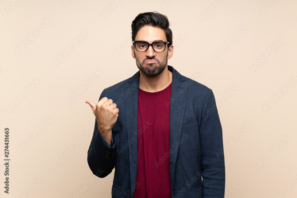 Handsome young man over isolated background unhappy and pointing to the side Handsome young man over isolated background unhappy and pointing to the side