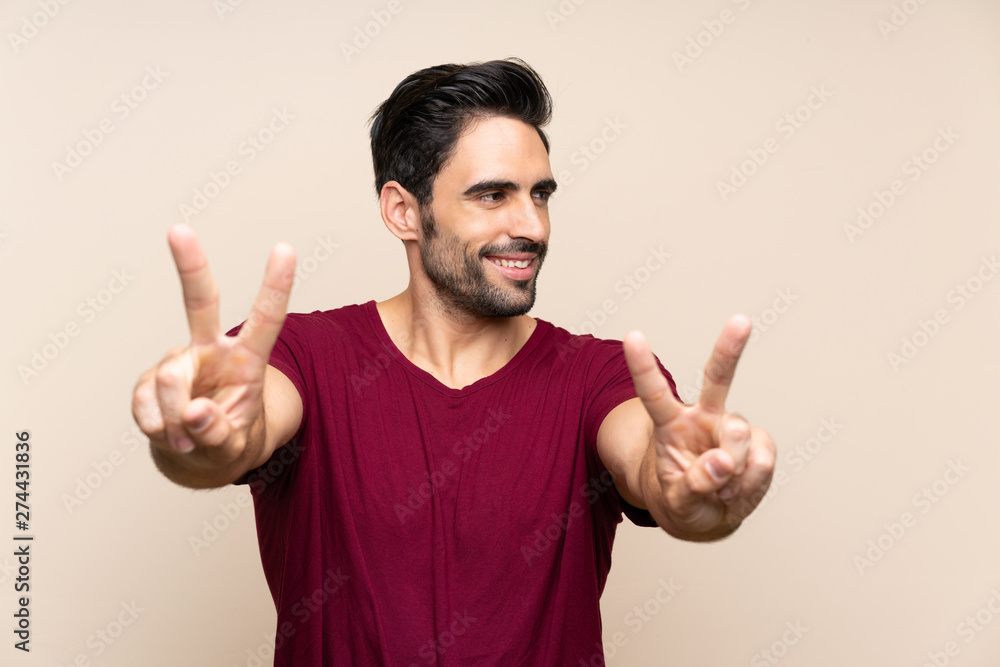 Handsome young man over isolated background smiling and showing victory sign Handsome young man over isolated background smiling and showing victory sign