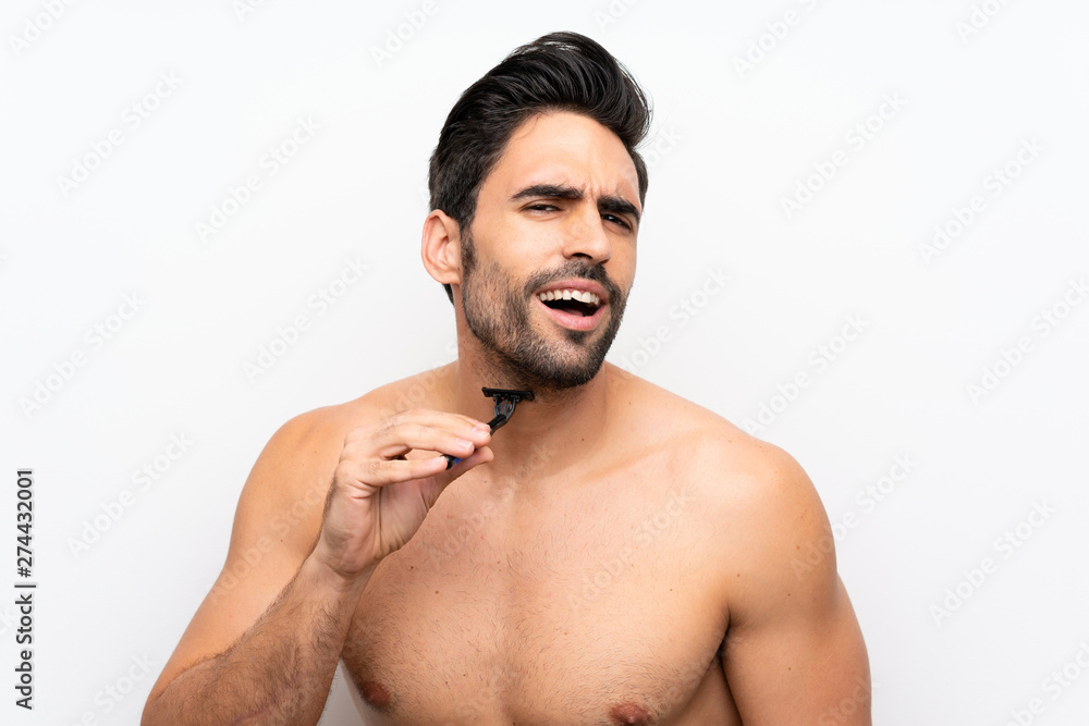Man shaving his beard over isolated white wall Man shaving his beard over isolated white wall