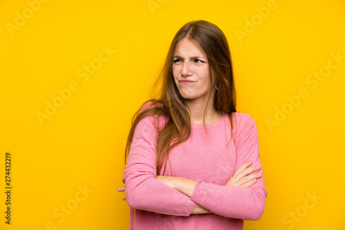 Young woman with long hair over isolated yellow wall with confuse face expression