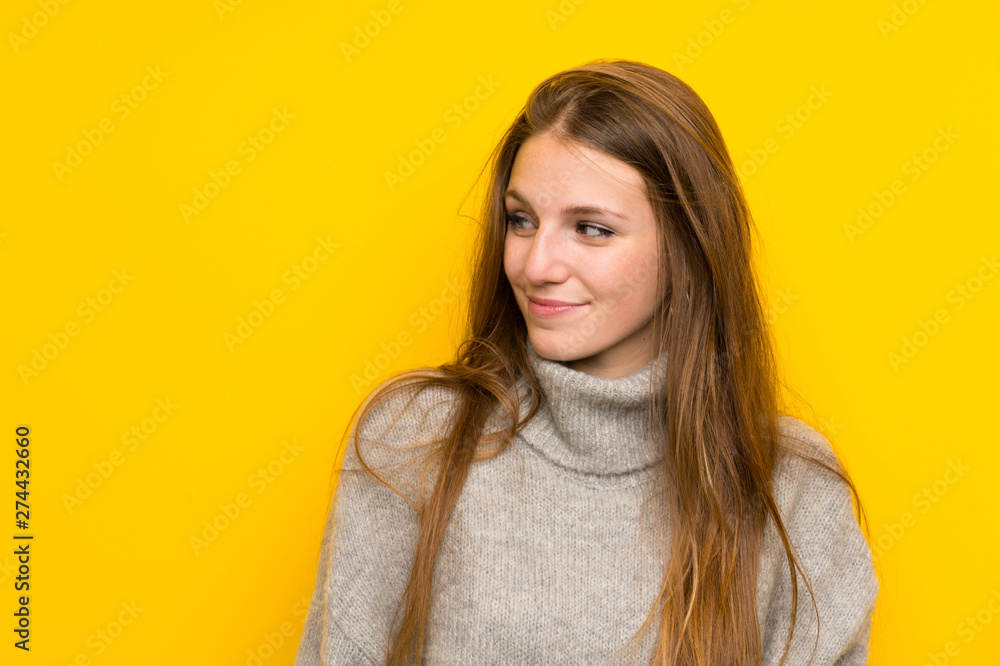 Young woman with long hair over yellow background standing and looking to the side Young woman with long hair over yellow background standing and looking to the side