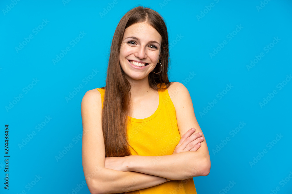 Young woman with long hair over isolated blue wall keeping the arms crossed in frontal position Young woman with long hair over isolated blue wall keeping the arms crossed in frontal position