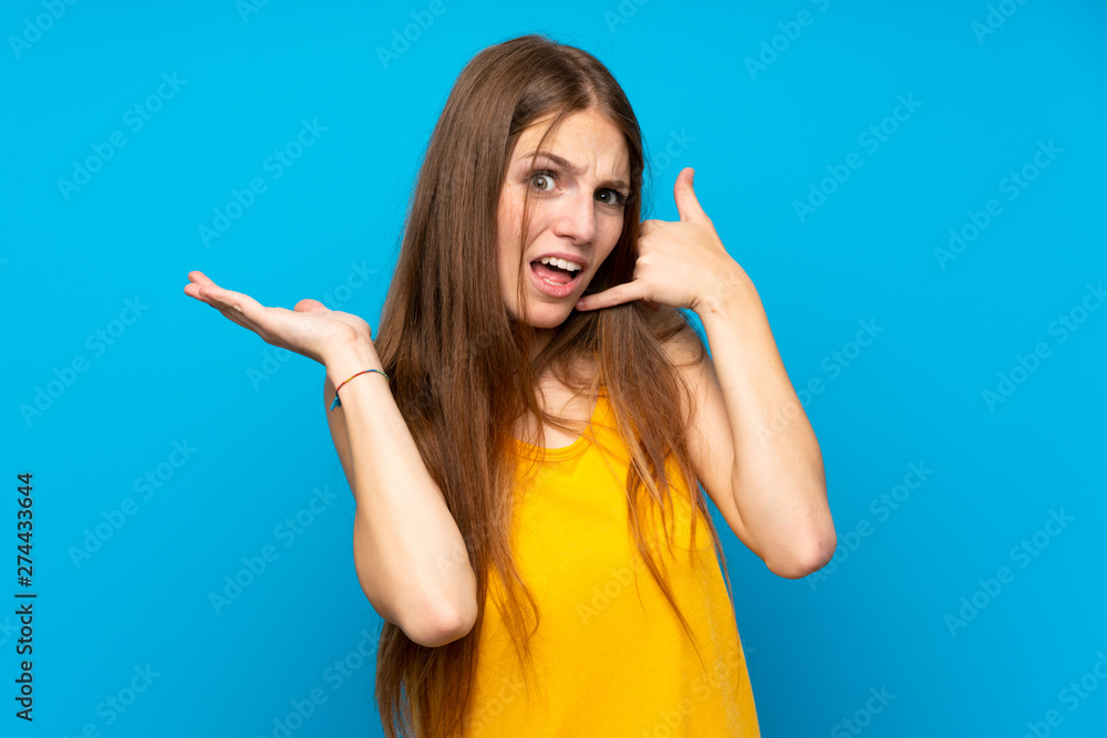 Young woman with long hair over isolated blue wall making phone gesture and doubting Young woman with long hair over isolated blue wall making phone gesture and doubting