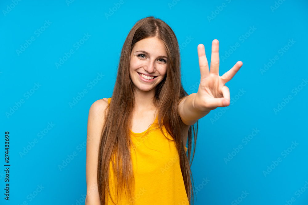 Young woman with long hair over isolated blue wall happy and counting three with fingers Young woman with long hair over isolated blue wall happy and counting three with fingers