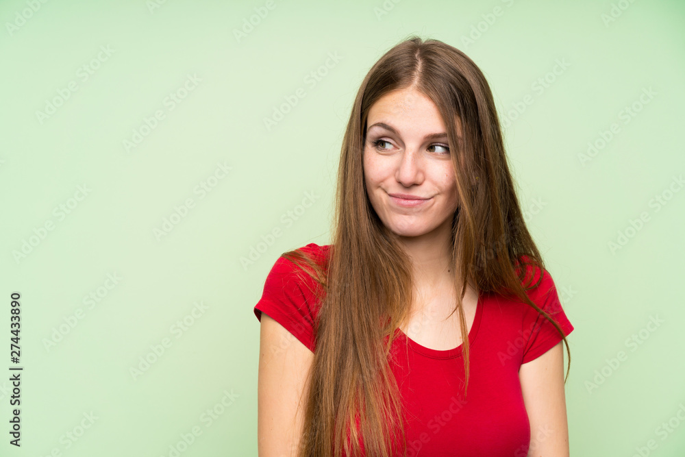 Obraz premium Young woman with long hair over isolated green wall standing and looking to the side