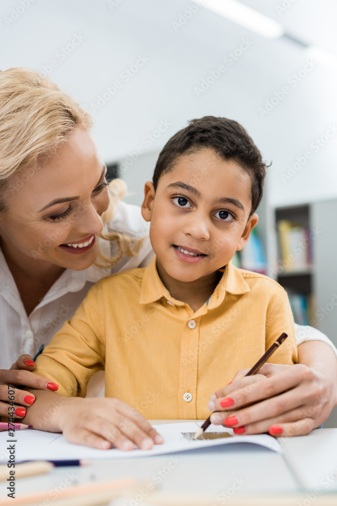 selective focus of happy woman looking at african american boy selective focus of happy woman looking at african american boy
