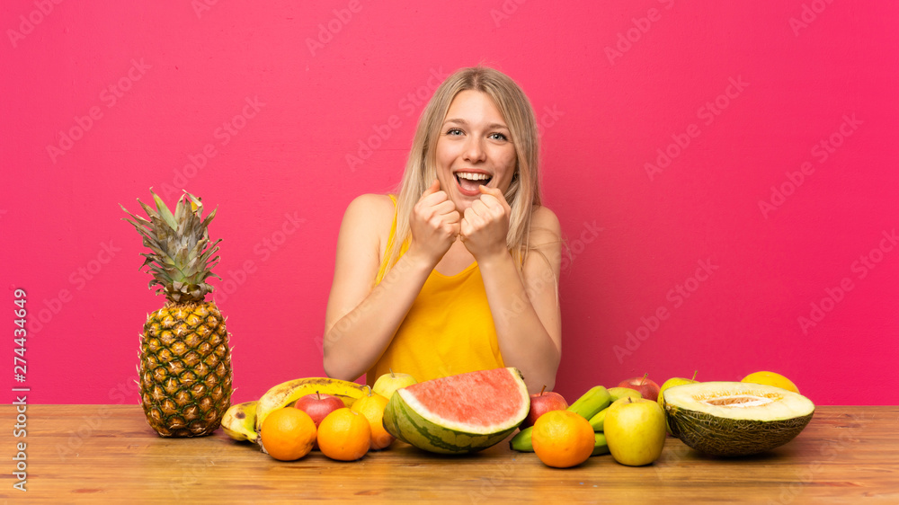 Young blonde woman with lots of fruits celebrating a victory Young blonde woman with lots of fruits celebrating a victory