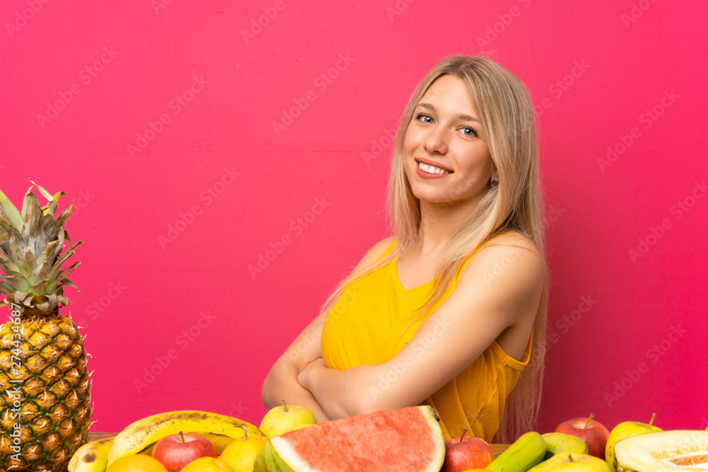 Young blonde woman with lots of fruits laughing Young blonde woman with lots of fruits laughing