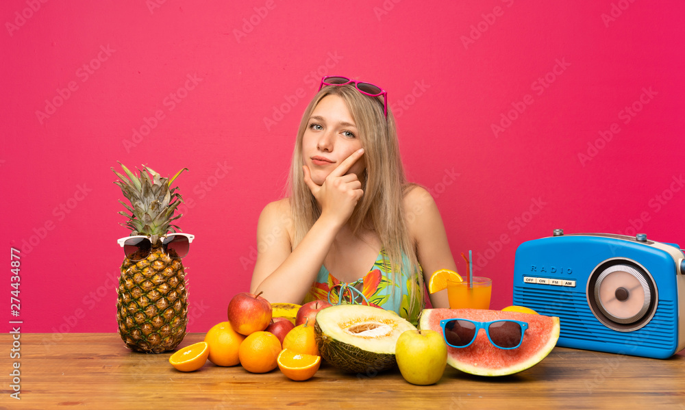 Young blonde woman with lots of fruits thinking an idea Young blonde woman with lots of fruits thinking an idea