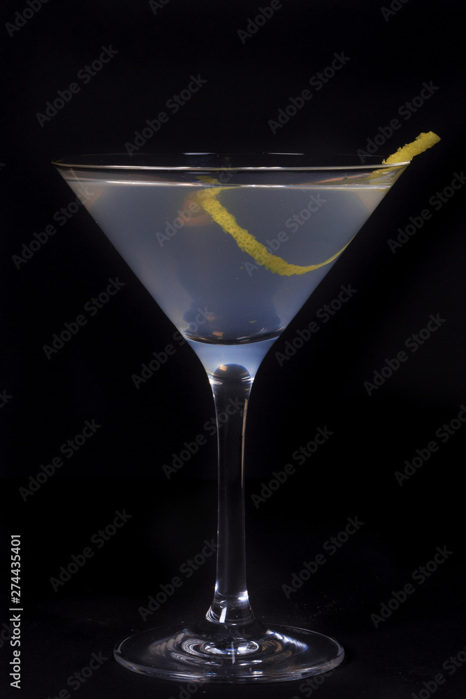 white lady cocktail with zest for taste in a martini glass, shot in classical perspective on a black background