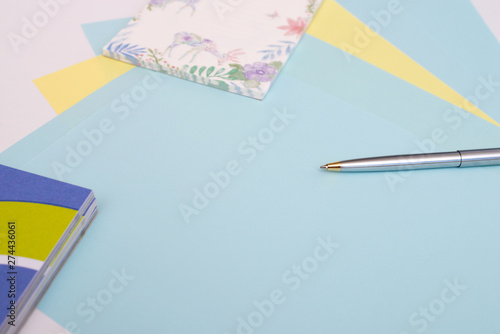 ballpoint pen lies on sheets of blue and yellow paper next to the notebook, white background, layout, Flatley