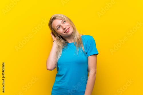 Young blonde woman over isolated yellow background thinking an idea