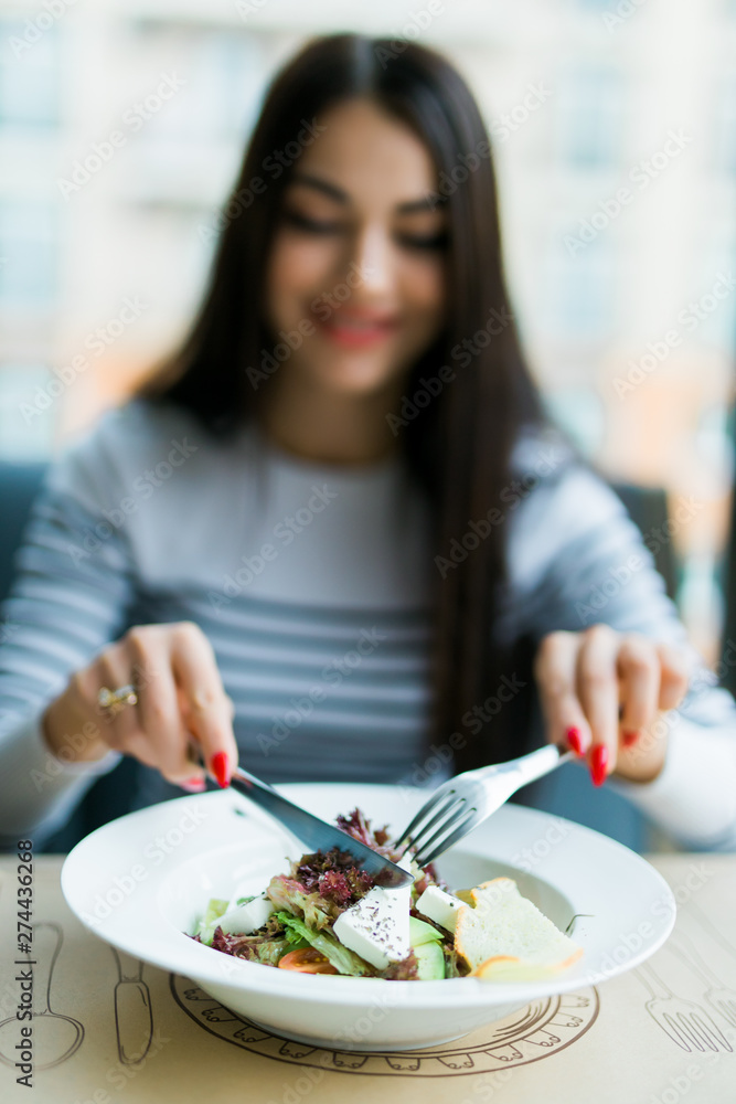 Young woman eating healthy food sitting in cafe