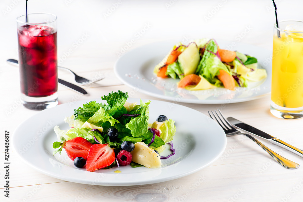 summer breakfast of fresh salad with berries, fruit and cheese and juice