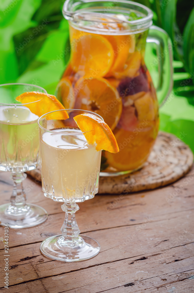 Fototapeta premium Glass of white sparkling wine sangria decorated with citrus slices and season fruits on wooden table.
