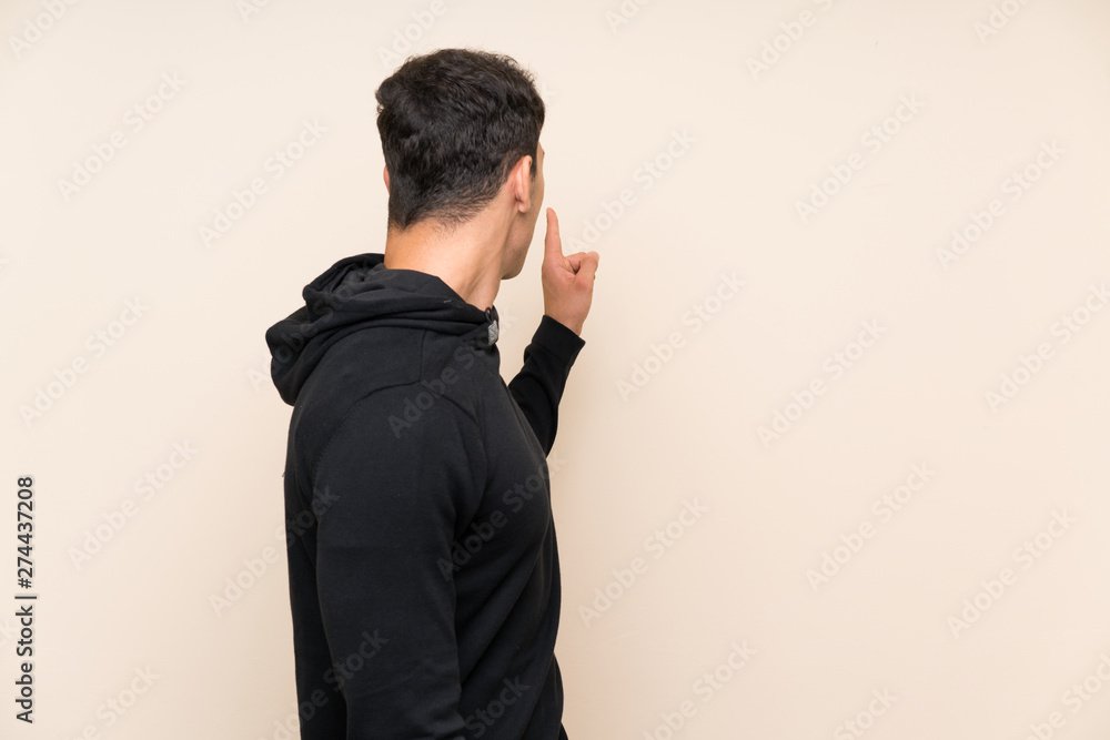 Handsome man over isolated background pointing back with the index finger Handsome man over isolated background pointing back with the index finger