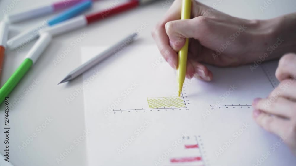 Woman fills data in graphs on paper. Records information. Woman is engaged in office work. Graphic charts,indicators. Woman works at the offside table. Woman draws symbols on the paper Woman fills data in graphs on paper. Records information. Woman is engaged in office work. Graphic charts,indicators. Woman works at the offside table. Woman draws symbols on the paper