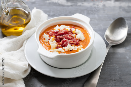 Typical Spanish soup salmorejo cream with ham and egg in white bowl on ceramic background. Top view. photo