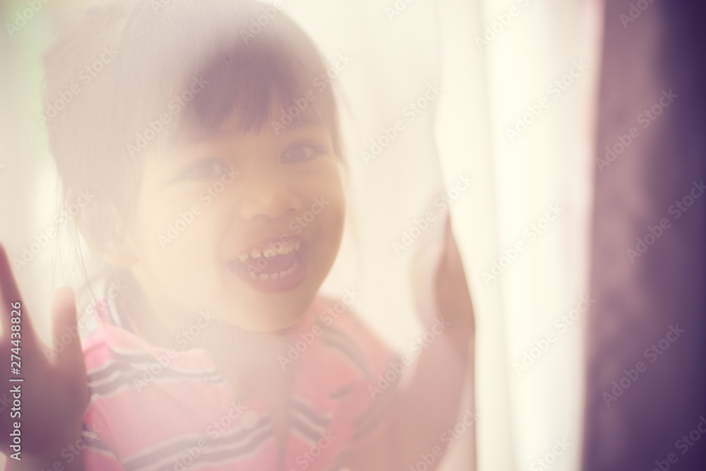 The little girl looks out because of curtains The little girl looks out because of curtains