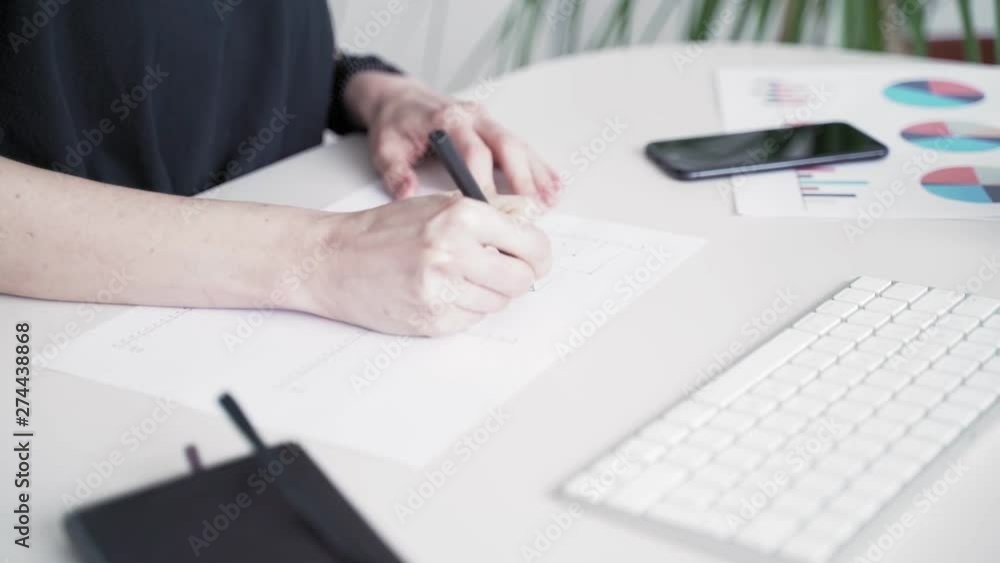 Woman fills data in graphs on paper. Records information. Woman is engaged in office work. Graphic charts,indicators. Woman works at the offside table. Woman draws symbols on the paper Woman fills data in graphs on paper. Records information. Woman is engaged in office work. Graphic charts,indicators. Woman works at the offside table. Woman draws symbols on the paper