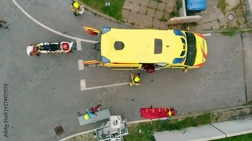 Slowly getting an injured person into an ambulance and now they will rush to the hospital. Aerial shot.