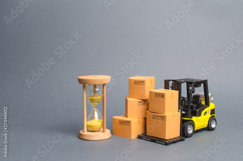 Yellow Forklift truck with cardboard boxes and a sand hourglass. Express delivery concept. Optimization of logistics and delivery, improving efficiency. Temporary storage, limited offer and discount. photo