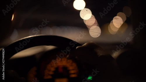 man driving car through tunnel in night time, hand on steering wheel with blurred street light bokeh