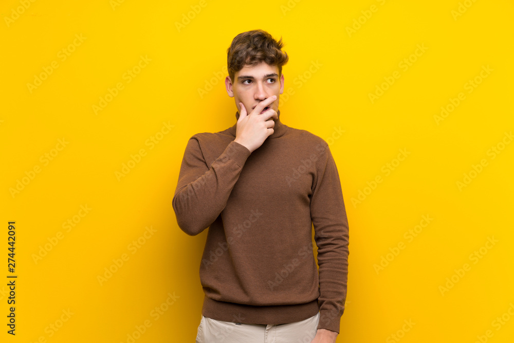Handsome young man over isolated yellow background surprised and shocked while looking right Handsome young man over isolated yellow background surprised and shocked while looking right