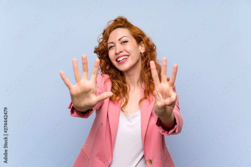 Redhead woman in suit over isolated blue wall counting eight with fingers Redhead woman in suit over isolated blue wall counting eight with fingers