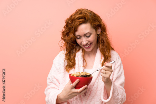 Redhead woman in dressing gown holding a bowl of cereals