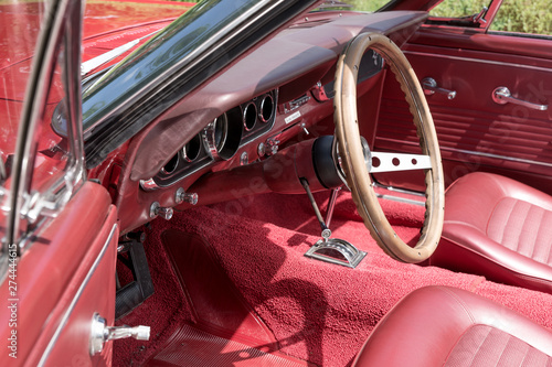 Interior view with instruments and wooden steering wheel of an old red cabriolet