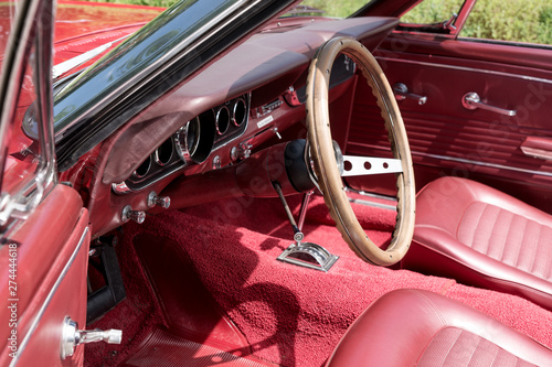 Interior view with instruments and wooden steering wheel of an old red cabriolet