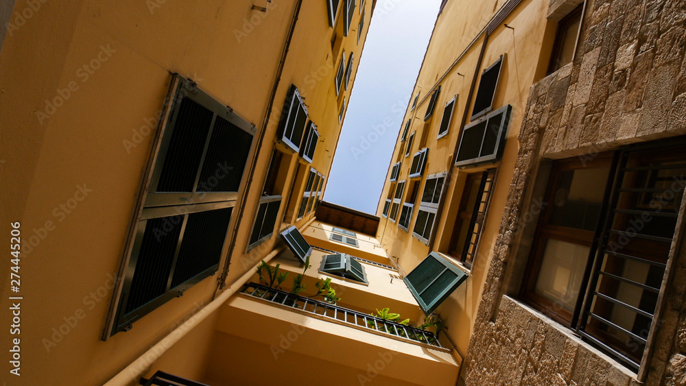 Fototapeta premium A view of a roofs from the narrow alley - yellow buildings and balcony