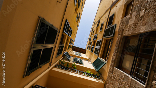 A view of a roofs from the narrow alley - yellow buildings and balcony