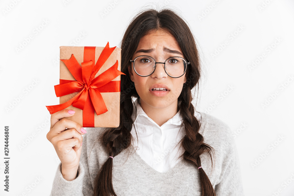 Confused young school girl isolated over white wall background holding surprise box gift. Confused young school girl isolated over white wall background holding surprise box gift.
