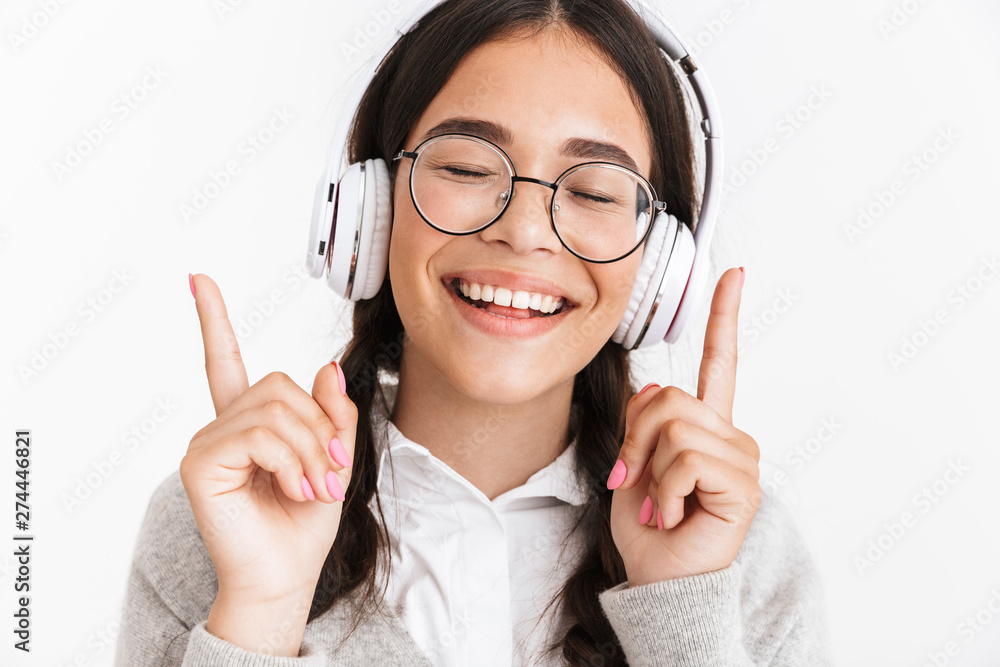 Photo closeup of lovely teenage girl wearing eyeglasses laughing while listening to music with headphones Photo closeup of lovely teenage girl wearing eyeglasses laughing while listening to music with headphones