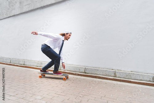 side view of handsome businessman riding on skateboard at street