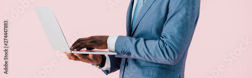 cropped view of african american businessman using laptop isolated on pink
