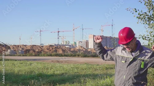 Dancing young engineer with helmet after work on the construction site. photo