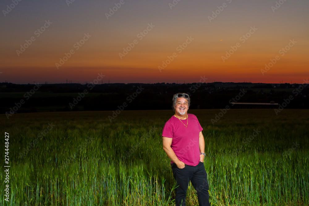 Gentleman poses standing at end of the day out in the field with the beautiful landscape that nature presents with the sunset. Gentleman poses standing at end of the day out in the field with the beautiful landscape that nature presents with the sunset.