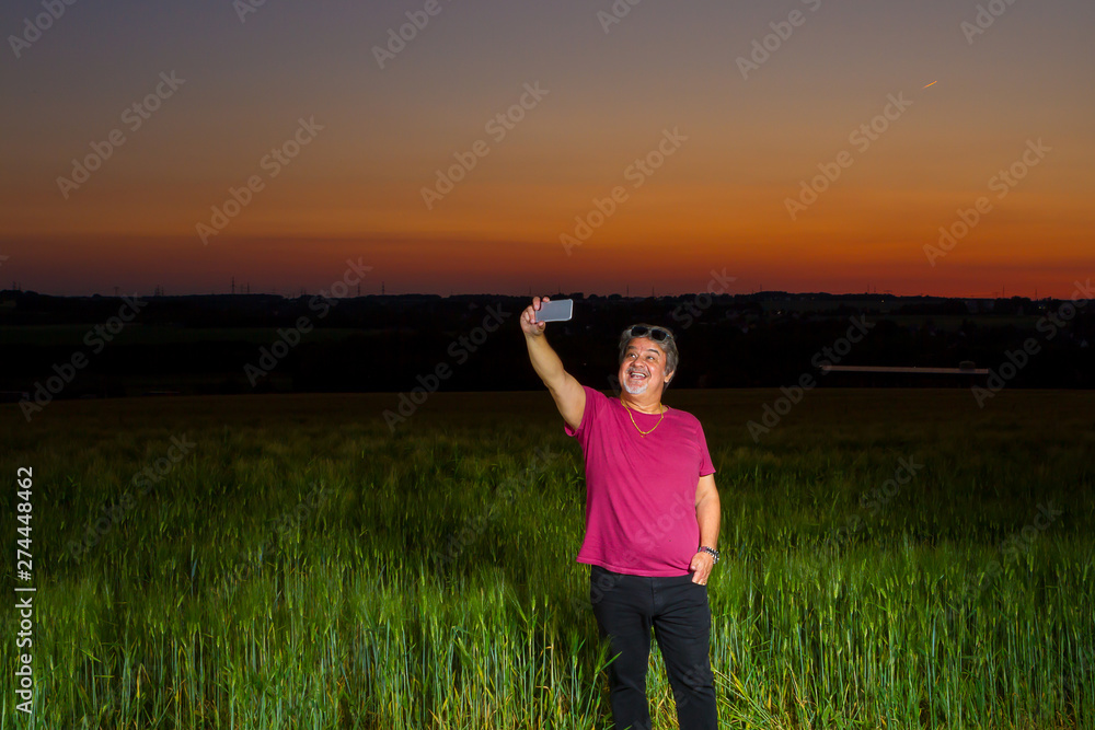 Man is taking a selfie at the end of the day out in the field with the beautiful landscape that nature presents with the sunset.